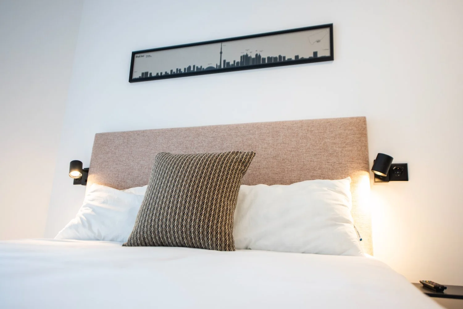 The Toronto room, sage headboard, a toucan-and-leaves cushion and the Toronto skyline with the CN Tower