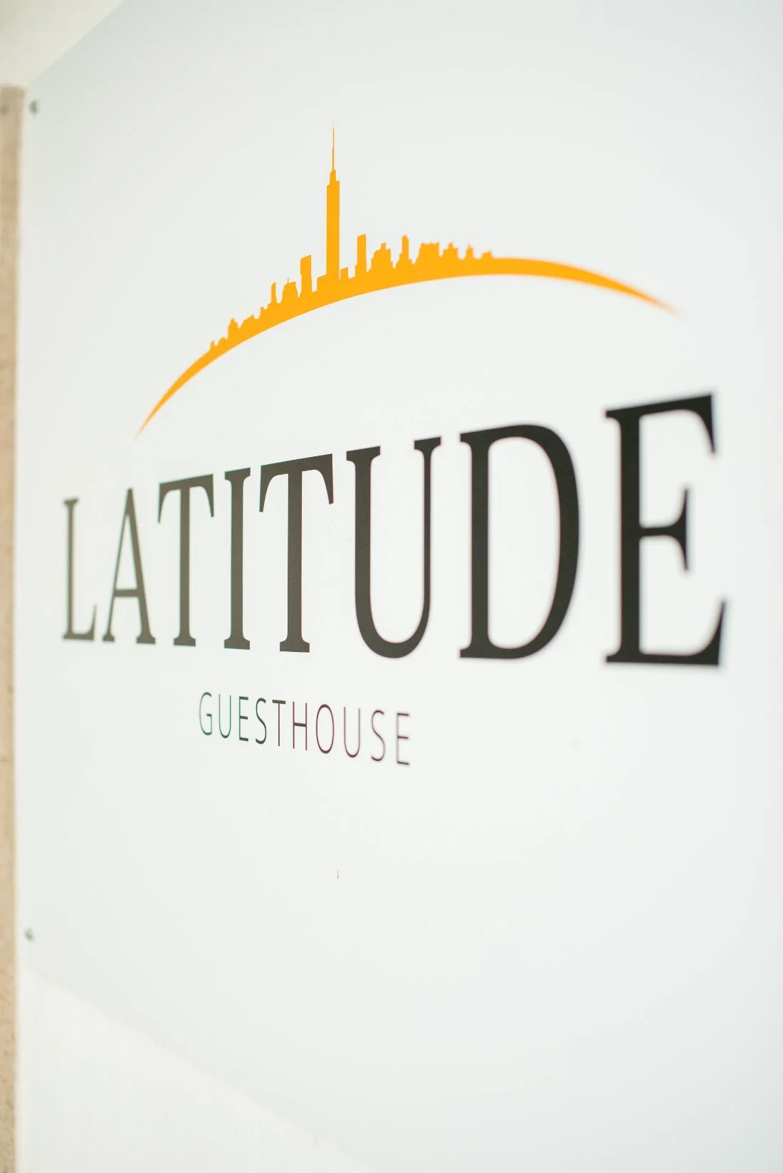 The Latitude Guesthouse sign, with its skyline logo on the wall
